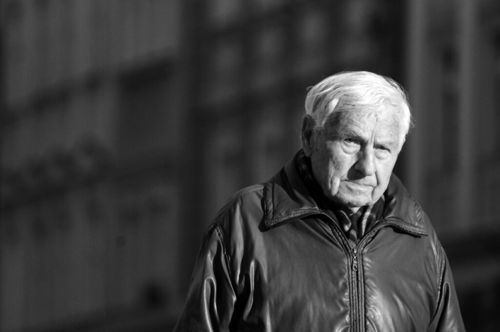 Black and white portrait of an elderly man with a solemn expression, emphasizing age and contemplation.